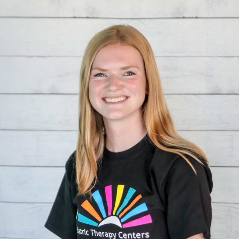 Autumn Reppe headshot photo with white wood background, bonnie has light brown hair and a CI Therapies black t-shirt on.