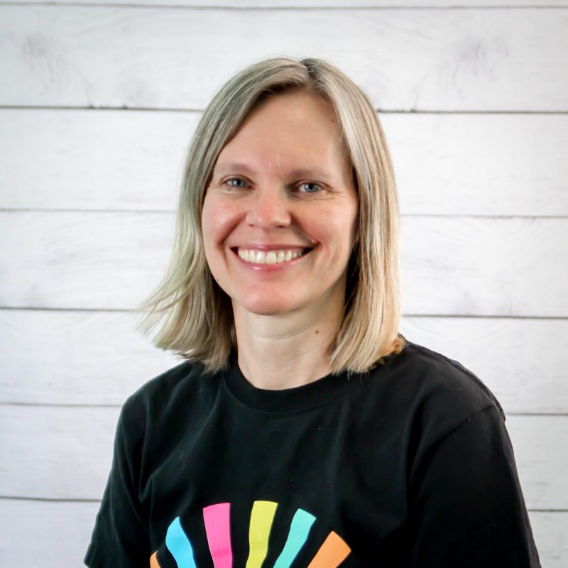 bonnie chester headshot photo with white wood background, bonnie has light brown hair and a CI Therapies black t-shirt on.