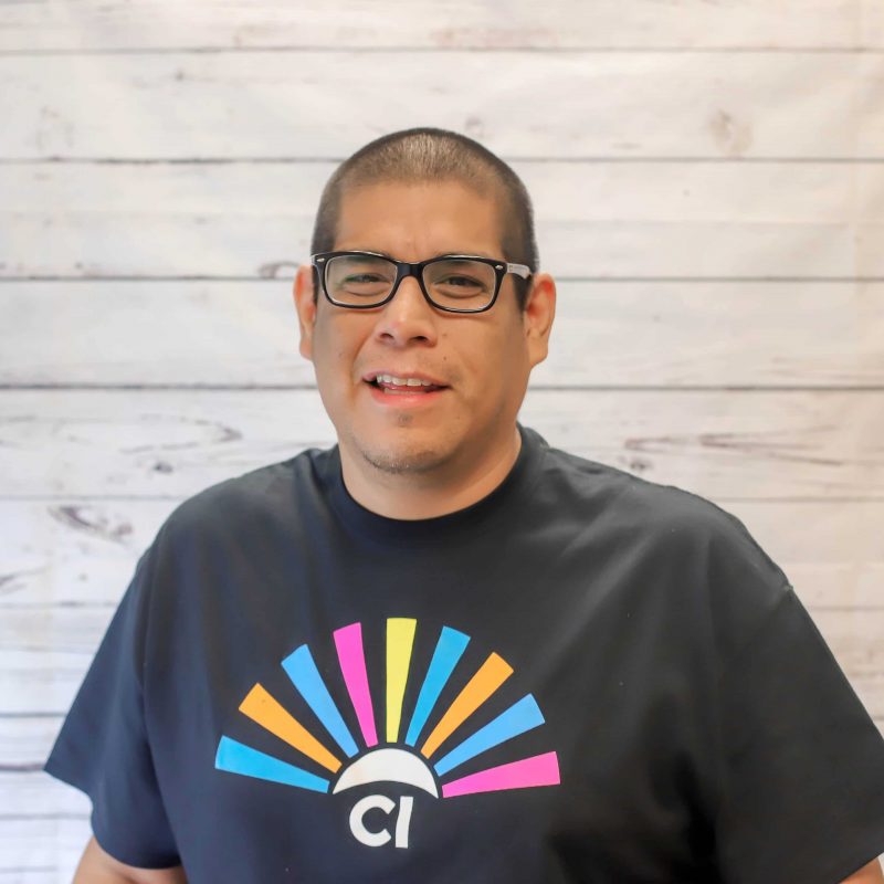 Carlos Valenzuela headshot photo with white wood background.